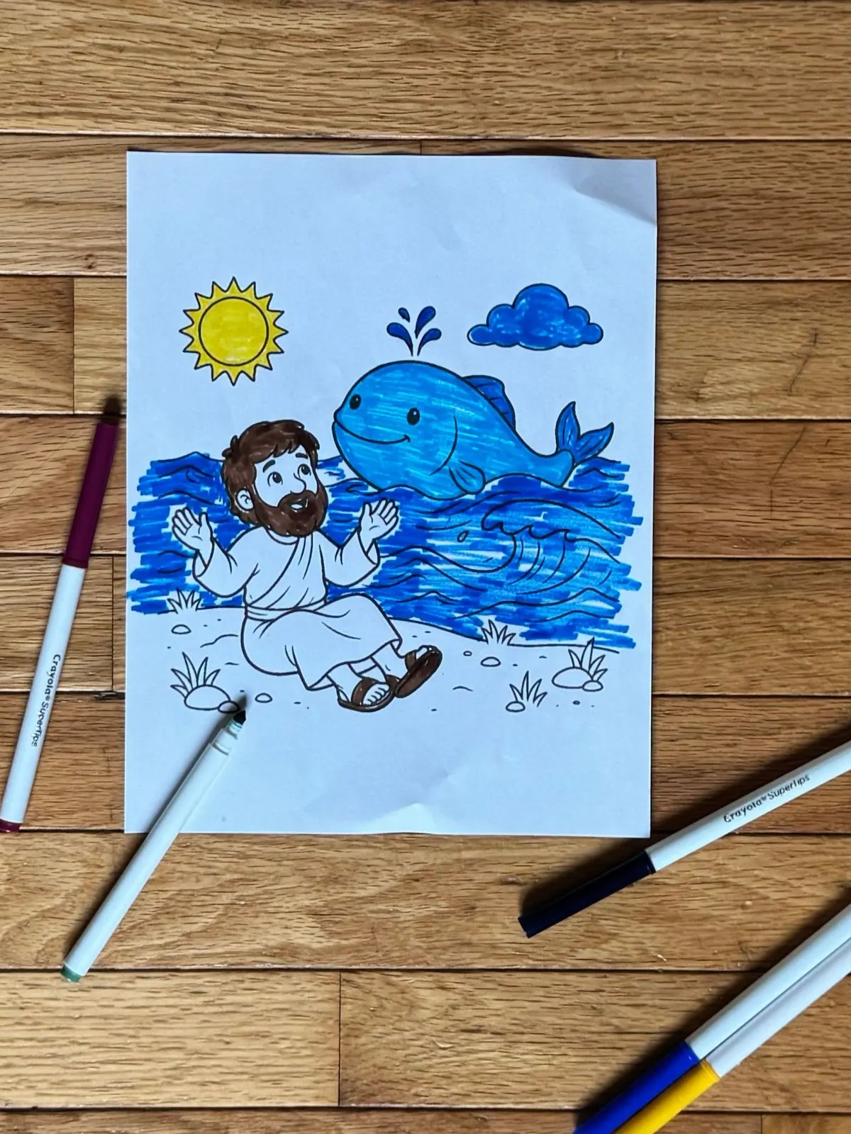A printed Jonah coloring page colored in with blue and yellow markers
